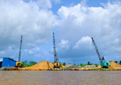 Cranes at construction site against sky