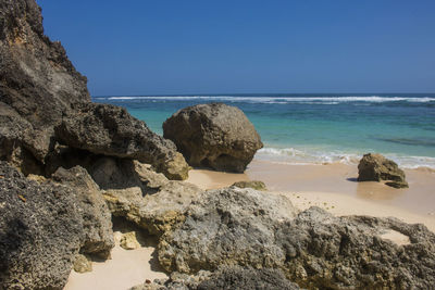 Rocks on beach against clear blue sky