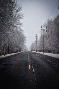 Road amidst trees against sky during winter