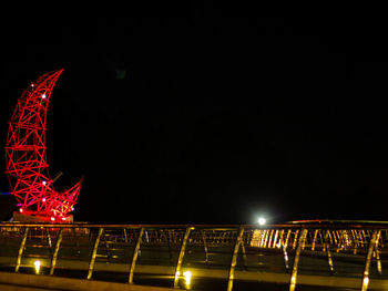 Low angle view of illuminated bridge against sky at night