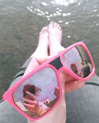 Low section of person on pink water at beach