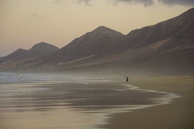 Scenic view of sea and mountains against sky