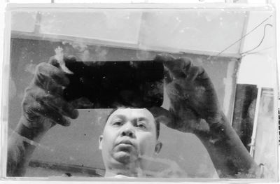 Portrait of boy photographing through glass window