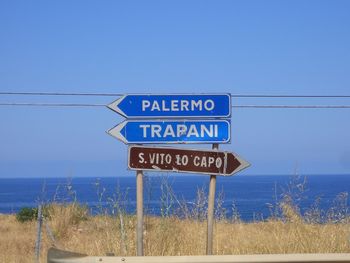 Information sign by sea against sky