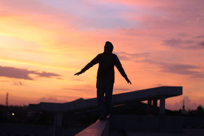 Silhouette man standing against orange sky