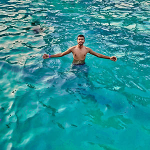 High angle view of shirtless man swimming in pool