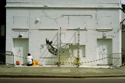 Rear view of woman crouching against building