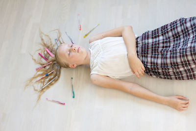 High angle view of girl sleeping by pens on floor