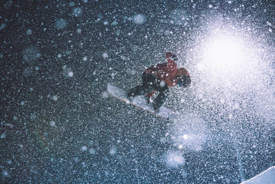 Low angle view of man snowboarding against sky during winter