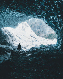 Rear view of silhouette man standing in sea during winter