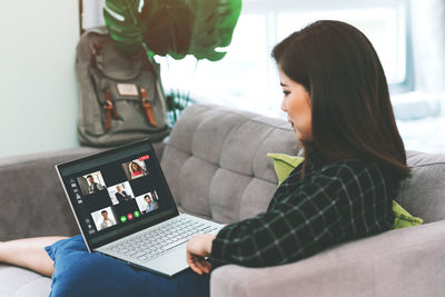 Woman using phone while sitting on sofa at home