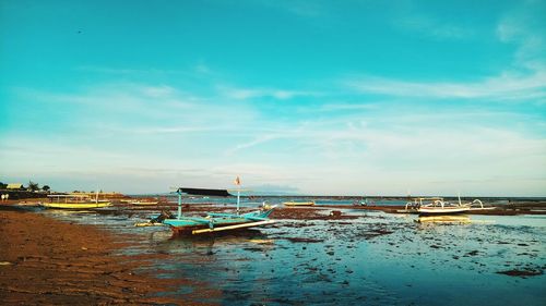 Boat moored on beach against sky