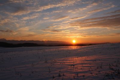 Scenic view of snow covered land during sunset