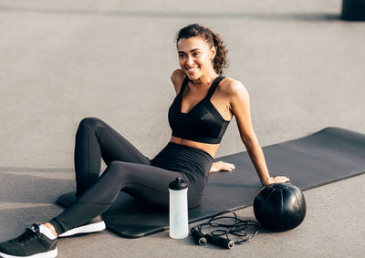 Smiling young woman sitting on exercise mat