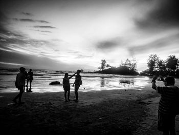 Silhouette people on beach against sky