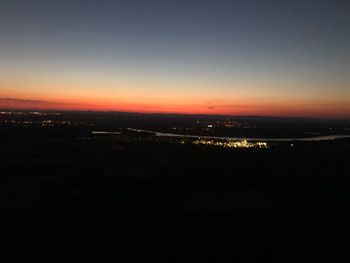 Aerial view of illuminated city against sky during sunset