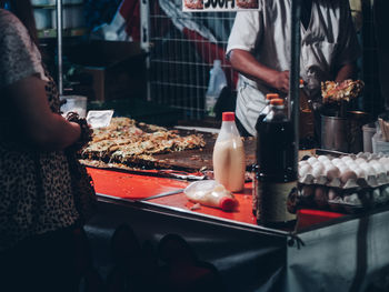 Midsection of people standing at restaurant in market