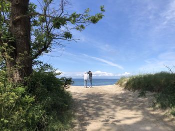 Rear view of man on beach against sky