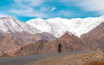 Rear view of man riding bicycle by mountains