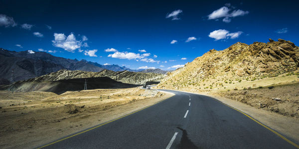 Road leading towards mountains against sky