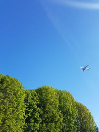 Low angle view of airplane flying against clear blue sky