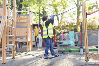 Side view of boy balancing on rope at playground