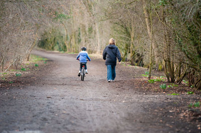 Rear view of woman riding bicycle on road