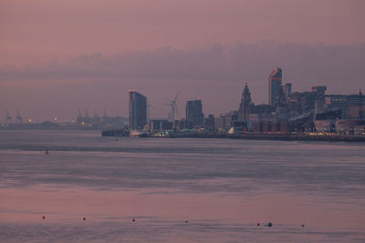 Buildings by sea with sky in background