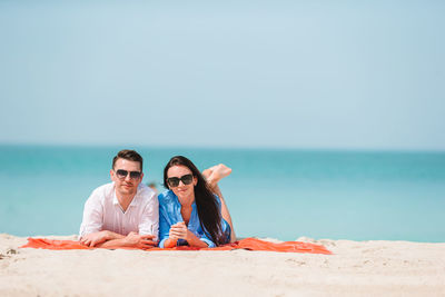 Young woman wearing sunglasses on beach against sky