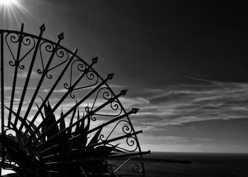 Low angle view of silhouette wheel by sea against sky