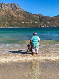 Rear view of woman on beach against sky