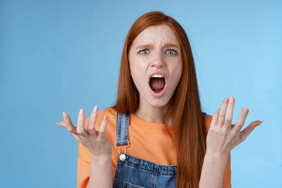 Portrait of young woman against blue background