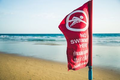 Close-up of flags on beach against sky