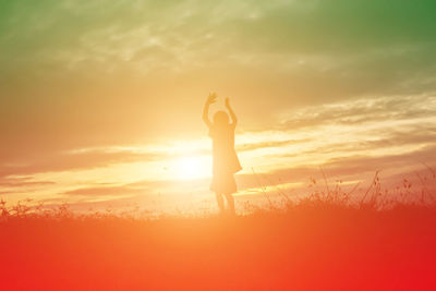 Silhouette woman standing on field against sky during sunset