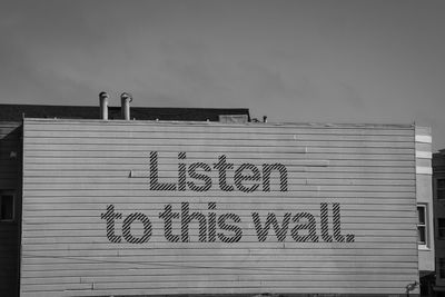 Low angle view of text on building against sky - listen to this wall