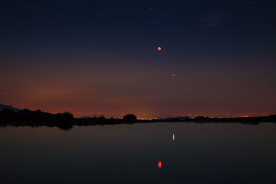 Scenic view of lake against sky at night