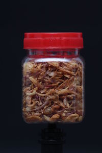 Close-up of meat in jar on table against black background