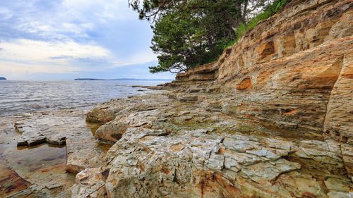 Rock formation on beach against sky