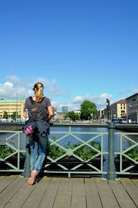 Full length of woman standing against blue sky