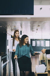 Multi-ethnic female colleagues going through check-in counter at airport