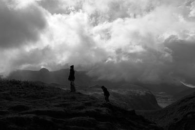 Woman and boy standing on mountain against sky
