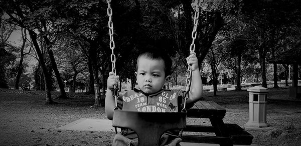 Boy sitting on swing at park