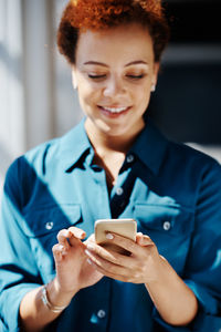 Smiling woman using phone at office