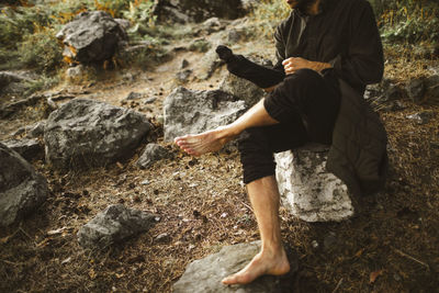 Low section of man sitting on rock in forest