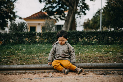 Portrait of boy sitting on bench in park