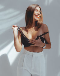 Beautiful young woman standing against white wall