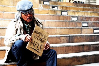 Beggar holding placard while sitting on steps