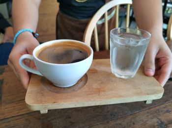 Coffee and drinking water in the barita hand on a wooden tray.