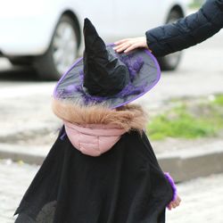 Rear view of girl witch costume walking on footpath