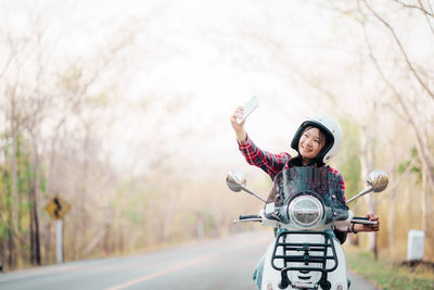 Portrait of smiling young woman standing on road